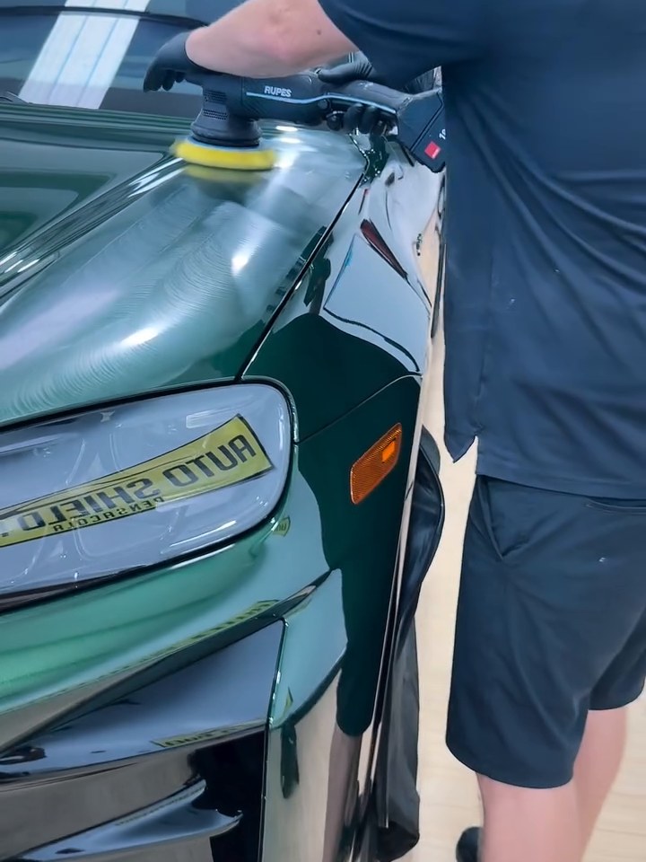 A machine polisher working across green paint in the shop
